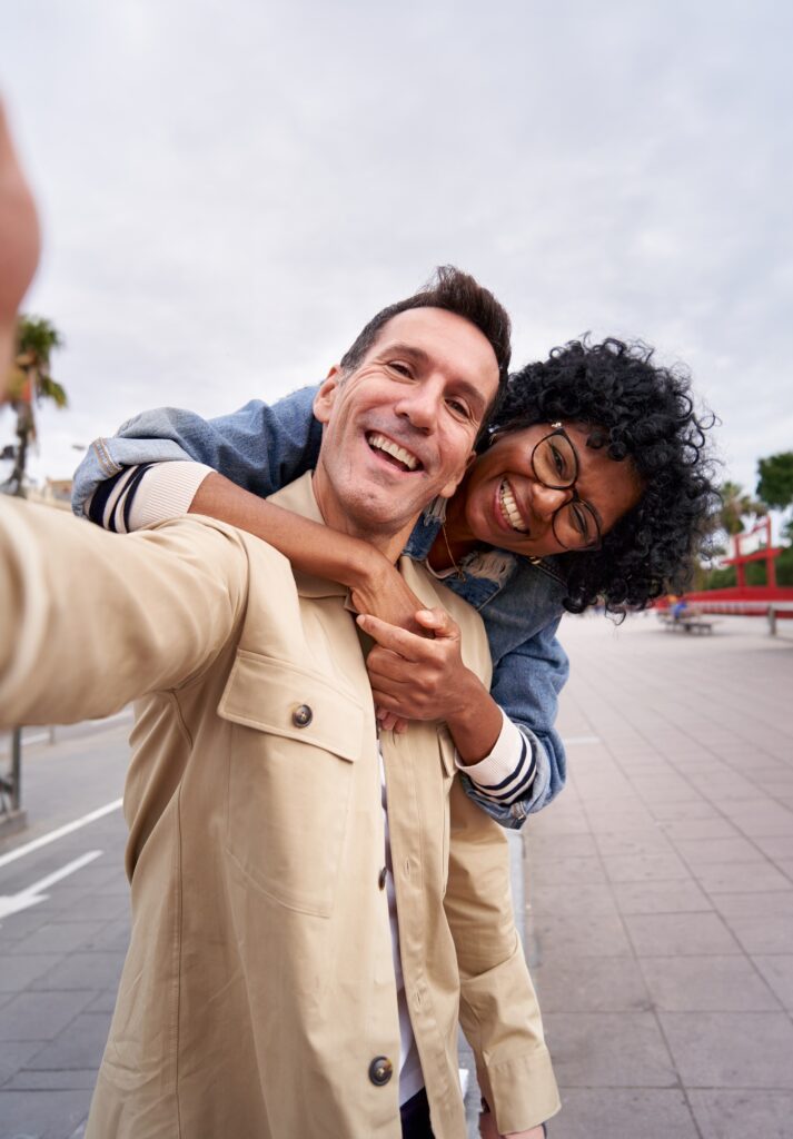 Happy middle-aged couple smiling at the camera while taking a selfie outdoors.