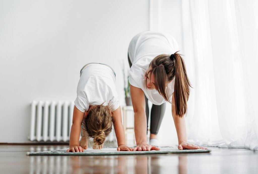 Happy mom and little daughter doing morning exercise together